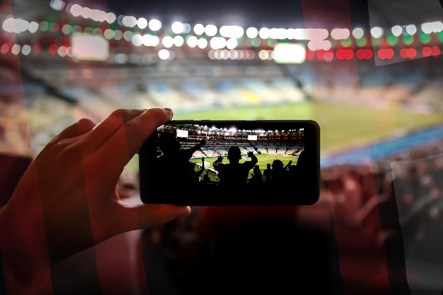 Pictured is a hand with a phone filming a soccer match against Milan AC